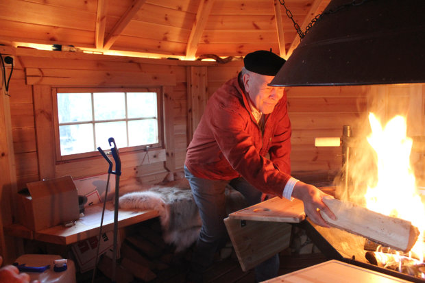 Timo Syväjärvi lisää klapia pesään viime vuonna Kuokkalankosken pohjapadolle valmistuneessa vieraskodassa. Kuva: Erkki Koivisto