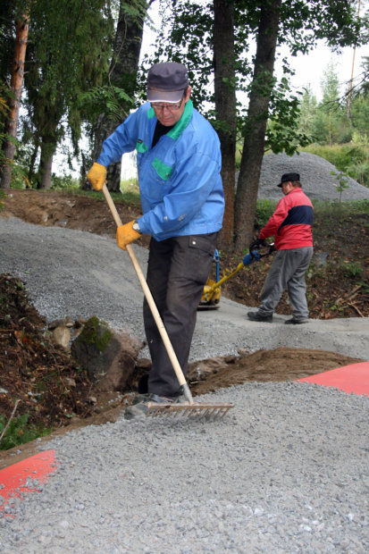 Matti Ollinpoika levittää kaivinkoneella polulle nostetut sorat.